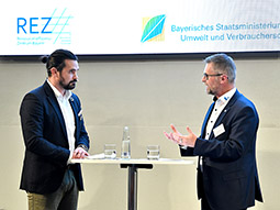 Lothar Schwarz von der INTERATIO-MediTec GmbH und August Wanninger von der Linhardt GmbH & Co. KG unterhalten sich im Dialog an einem Stehtisch.